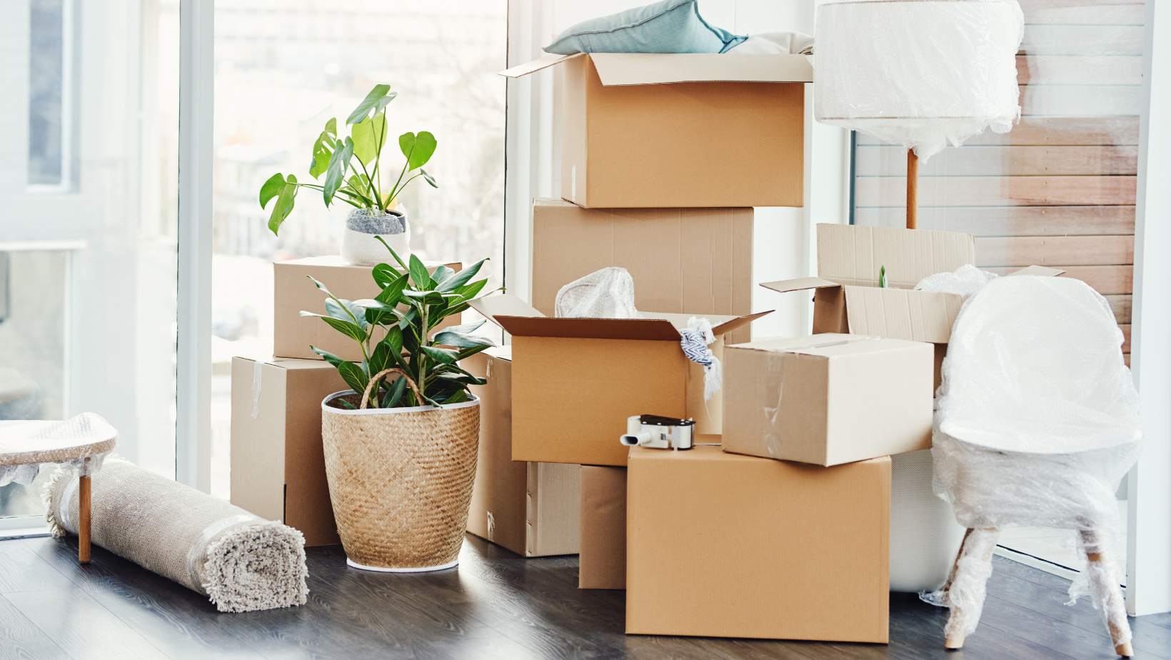 Stacks of furniture and boxes that are packed and covered in bubble wrap