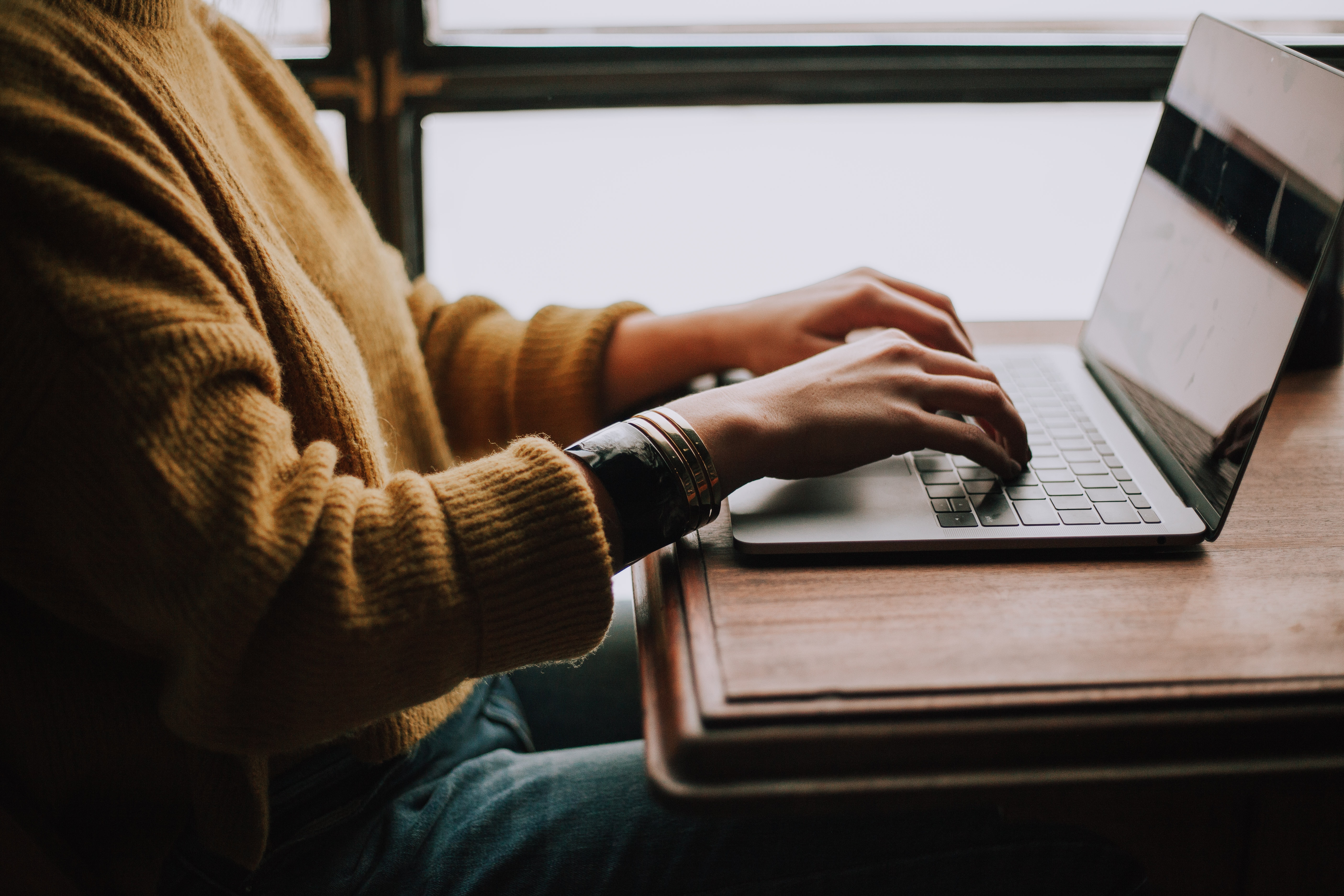 Women sitting at a table typing on a laptop